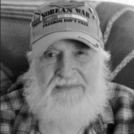 services for veterans: black and white image of veteran wearing korean war hat that says 'freedom isn't free'