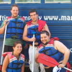 VOA Northern New England behavioral health services: group of four young adults smiling at a rafting event, wearing lifejackets