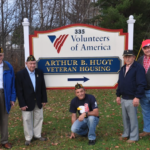 Arthur B. Huot House sign with veterans standing next to it and smiling