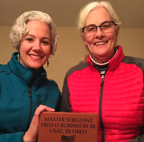 two women holding a memorial plaque